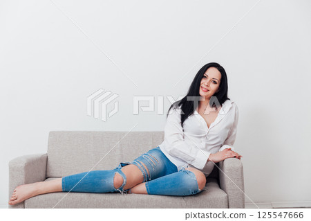 woman relaxing on gray office sofa in white room interior 125547666