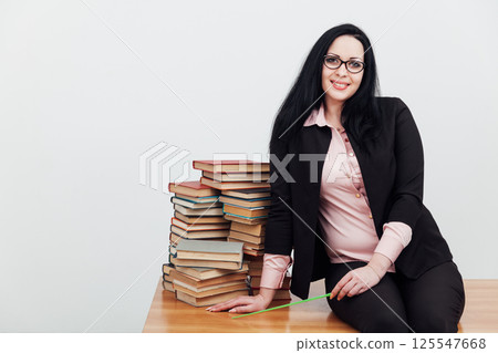 Woman teacher in suit and table with stacks of library books 125547668