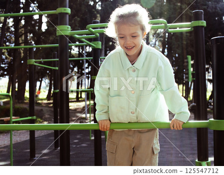 little cute girl with her mother and twin sister having fun on training playground outside 125547712