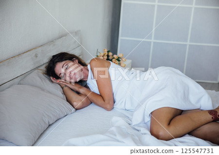 Woman in lingerie sleeping and smiling in a dream in bedroom on bed Woman in lingerie sleeping and smiling in a dream in bedroom on bed 125547731