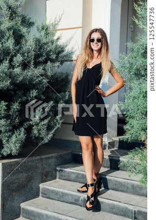 woman in black summer dress standing on stairs 125547736