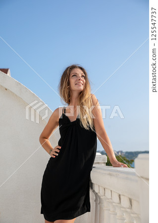 woman in black summer dress posing and walking around town 125547737
