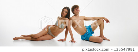 Confident young woman and man, stylish couple relaxing in stylish beachwear, posing against white studio background. 125547991