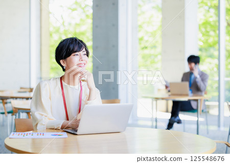 Businesswoman working on a computer in a cafe Businesswoman working on a computer in a cafe 125548676