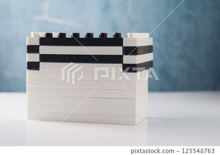 The photo shows fragments of a children's plastic construction set, randomly assembled together. The plastic pieces of the set come in various shapes and sizes. The photo shows fragments of a children's plastic construction set, randomly assembled together. The plastic pieces of the set come in various shapes and sizes. 125548763