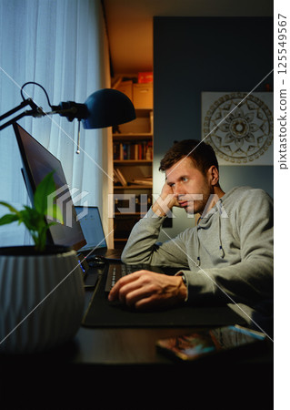 Man procrastinating at workplace while browsing on computer 125549567