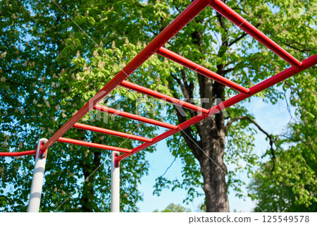 Red outdoor monkey bars in park with green trees Red outdoor monkey bars in park with green trees 125549578