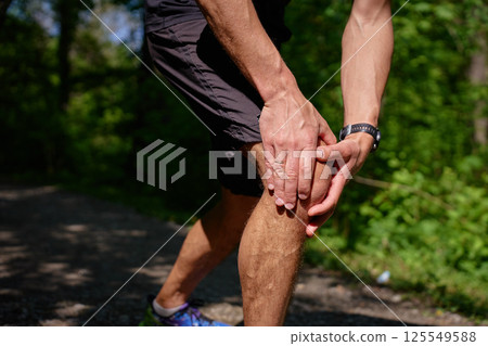 Man suffering from knee pain during running in park 125549588