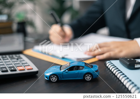 Dealership offered various finance options, including an auto loan or lease, making it easier to buy or rent a car from the company. Agent reviewed contract, finalizing insurance agreement. Dealership offered various finance options, including an auto loan or lease, making it easier to buy or rent a car from the company. Agent reviewed contract, finalizing insurance agreement. 125550621