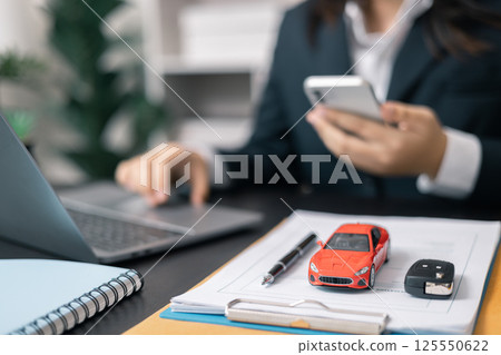 Dealership offered various finance options, including an auto loan or lease, making it easier to buy or rent a car from the company. Agent reviewed contract, finalizing insurance agreement. Dealership offered various finance options, including an auto loan or lease, making it easier to buy or rent a car from the company. Agent reviewed contract, finalizing insurance agreement. 125550622