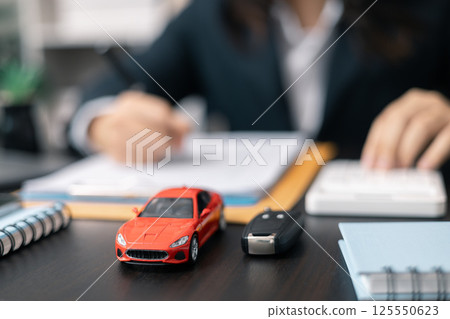 Dealership offered various finance options, including an auto loan or lease, making it easier to buy or rent a car from the company. Agent reviewed contract, finalizing insurance agreement. 125550623