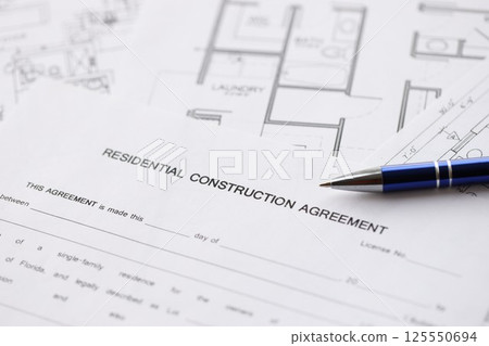 Pen on residential construction agreement and planning blueprints of residential building project close up. Construction plan concept 125550694