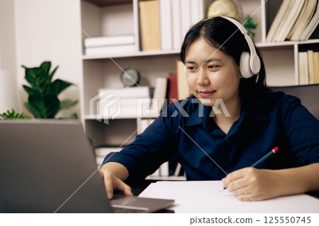 Online academy, student and woman conduct research on their laptops, people work on desktops in office. Young person utilizes technology and cyberspace for studying, preparing for university exam. 125550745