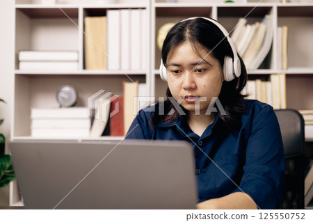 Online academy, student and woman conduct research on their laptops, people work on desktops in office. Young person utilizes technology and cyberspace for studying, preparing for university exam. 125550752