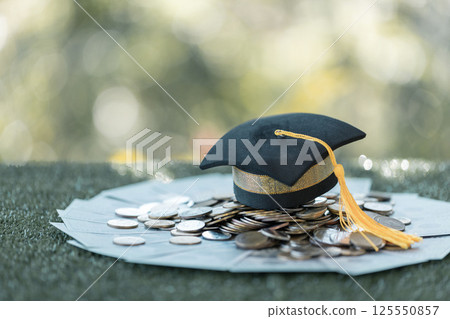 Graduation from college with university degree in finance marked successful culmination of education, envisioning value of each coin invested. coin, college, education, graduation, hat, school. Graduation from college with university degree in finance marked successful culmination of education, envisioning value of each coin invested. coin, college, education, graduation, hat, school. 125550857