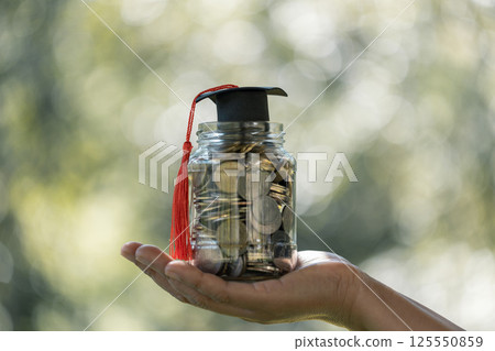 Graduation from college with university degree in finance marked successful culmination of education, envisioning value of each coin invested. coin, college, education, graduation, hat, school. Graduation from college with university degree in finance marked successful culmination of education, envisioning value of each coin invested. coin, college, education, graduation, hat, school. 125550859