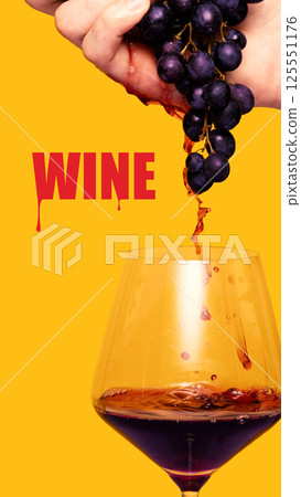 Hand squeezing juicy grapes into wine glass against bold yellow background creating dynamic wine imagery. 125551176