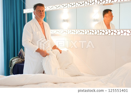 Morning chores, man in robe making bed after sleep, daily household duties 125551401
