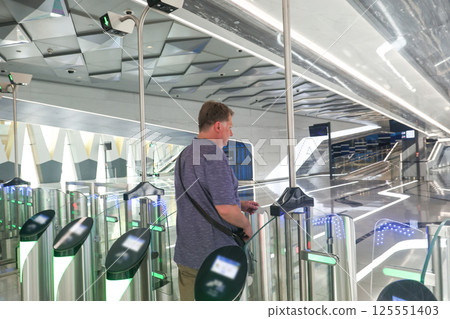 A man passes through a metro turnstile paying for his ride with a credit card 125551403
