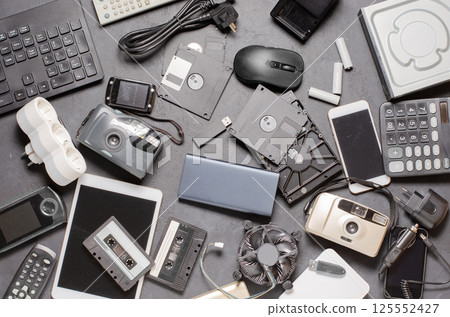 Old electronic devices on a black background. The concept of recycling used gadgets. Old electronic devices on a black background. The concept of recycling used gadgets. 125552427