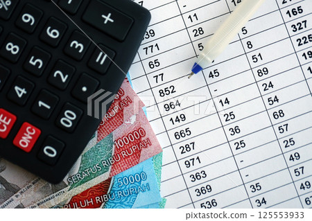 Business calculations with indonesian rupiah money bills and calculator with pen on office table close up. The concept of business and taxpaying in Indonesia Business calculations with indonesian rupiah money bills and calculator with pen on office table close up. The concept of business and taxpaying in Indonesia 125553933