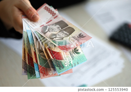 Female accountant hand give bunch of many indonesian rupiah money bills of new series close up Female accountant hand give bunch of many indonesian rupiah money bills of new series close up 125553940