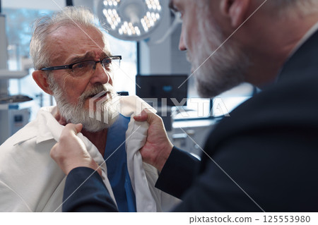Aggressive man have conflict with doctor, holding him by coat. 125553980