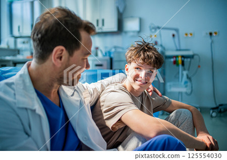 Compassionate doctor supporting anxious teenage patient before surgery. Compassionate doctor supporting anxious teenage patient before surgery. 125554030