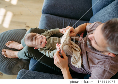 Top view of father holding baby boy on his lap. Top view of father holding baby boy on his lap. 125554071