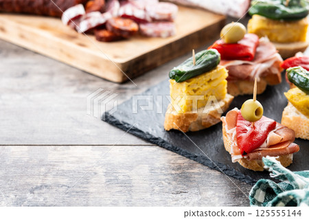 Traditional Spanish pintxos on wooden table 125555144