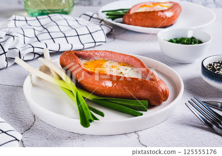 Fried egg in a sausage in the form of khachapuri on a plate on the table Fried egg in a sausage in the form of khachapuri on a plate on the table 125555176