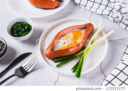 Sausage filled with fried egg and garlic on a plate on a table Sausage filled with fried egg and garlic on a plate on a table 125555177