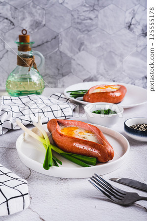 Fried egg in a sausage in the form of khachapuri on a plate on the table vertical view Fried egg in a sausage in the form of khachapuri on a plate on the table vertical view 125555178