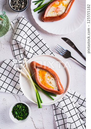 Sausage filled with fried egg and garlic on a plate on a table top and vertical view Sausage filled with fried egg and garlic on a plate on a table top and vertical view 125555182