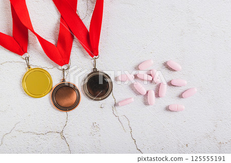 Medals and doping pills on gray background top view Medals and doping pills on gray background top view 125555191