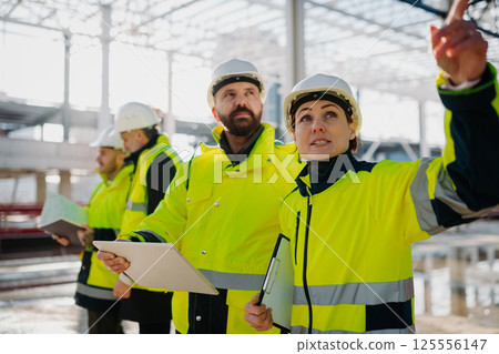 Team of engineers and construction workers inspecting building progress. Team of engineers and construction workers inspecting building progress. 125556147