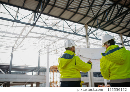 Construction managers reviewing blueprints or project plans. 125556152