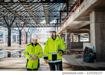 Engineers discussing construction plans using a tablet on site. 125556157