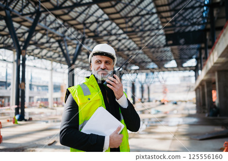 Site manager giving instructions over radio during building inspection. 125556160