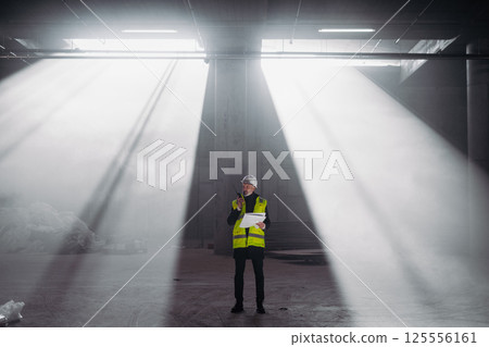 Construction foreman giving instructions over radio during building inspection. 125556161