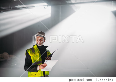 Construction foreman giving instructions over radio during building inspection. 125556164