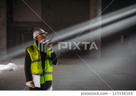 Construction foreman giving instructions over radio during building inspection. 125556165