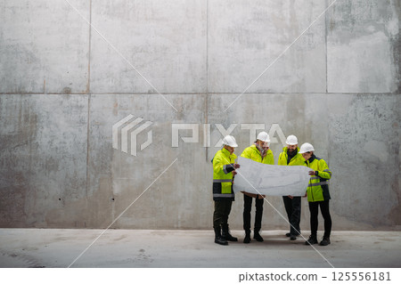 Team of engineers and construction workers reviewing blueprints, building site. Team of engineers and construction workers reviewing blueprints, building site. 125556181