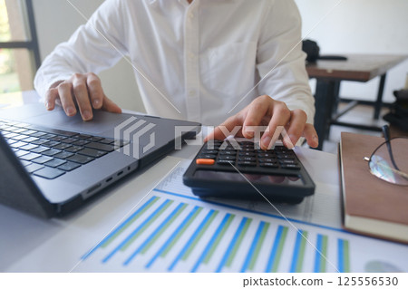 Close up accountant banker or bookkeeper making calculations with calculator. 125556530