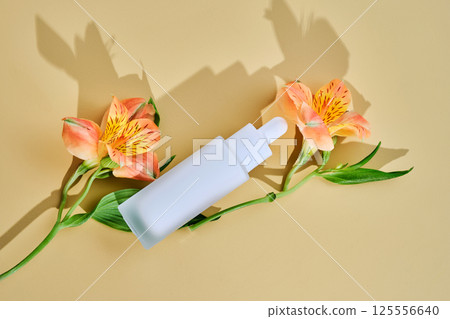 Regenerating serum with lifting effect on beige background with lilies. Regenerating serum with lifting effect on beige background with lilies. 125556640