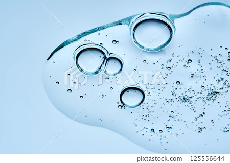 A beautiful swatch of hyaluronic serum with bubbles on a blue background. View from below. A beautiful swatch of hyaluronic serum with bubbles on a blue background. View from below. 125556644