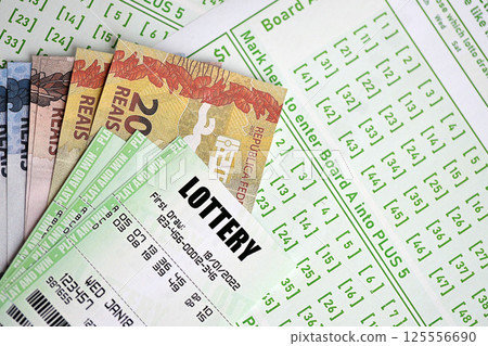 Green lottery tickets and brazilian reals money bills on blank with numbers for playing lottery Green lottery tickets and brazilian reals money bills on blank with numbers for playing lottery 125556690