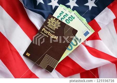 Red Portugal passport of European Union and money on United States national flag background Red Portugal passport of European Union and money on United States national flag background 125556716