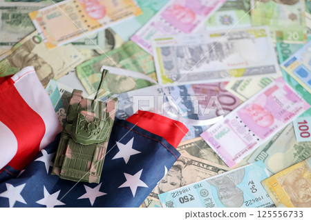 Tank on United States flag on many banknotes of different currency. Background of war funding Tank on United States flag on many banknotes of different currency. Background of war funding 125556733