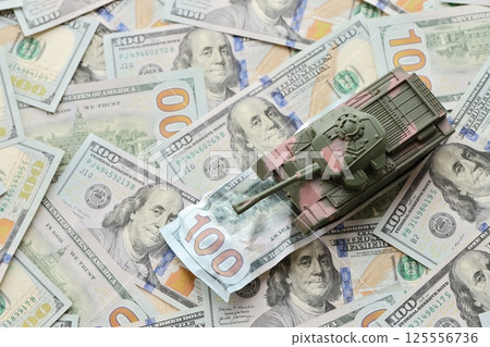 Tank on crumpled hundred dollar bills banknotes. Background of war funding and military support 125556736